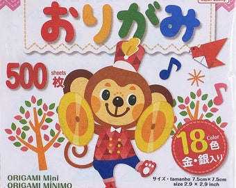 May include: A packet of origami paper featuring a cartoon monkey playing cymbals. The packaging displays the word "origami" and "500 sheets". The packet also includes the text "ORIGAMI Mini" and "size 7.5cm x 7.5cm".