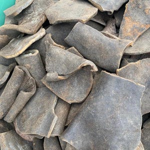 May include: A close-up shot of a pile of irregularly shaped, dark gray pieces. The pieces have a rough, textured surface and varying shades of gray and brown. The items appear to be organic and possibly dried.