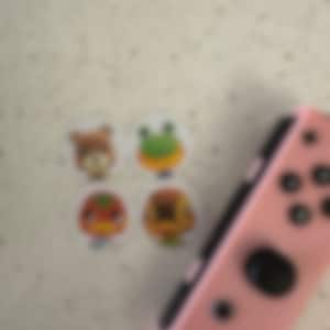 May include: A white ceramic mug with a black handle and the text "But First, Coffee" in a bold, black font. The mug is set against a blurred background, suggesting a cozy setting. The mug appears to be approximately 4 inches tall.