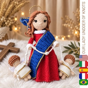 Puede incluir: Una muñeca de ganchillo de una figura con cabello castaño y un halo dorado, vistiendo un vestido rojo con una banda azul, sosteniendo dos figuras de ángeles de ganchillo más pequeñas con cordones blancos. El texto OUR LADY UNDOER OF KNOTS es visible.