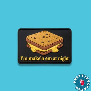 May include: A rectangular black patch featuring a graphic of a grilled cheese sandwich with melted yellow cheese dripping from the sides. The text "I'm make'n em at night" is printed in yellow lettering below the sandwich illustration.