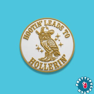 May include: A round, white patch with a gold border and an owl wearing a cowboy hat and boots. The text "HOOTIN' LEADS TO HOLLERIN'" is in gold around the owl. The patch has a blue background.