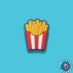 May include: A colorful patch featuring a cartoon depiction of a container of french fries. The fries are yellow, and the container is red with white stripes. The patch has a blue border and is set against a turquoise background.