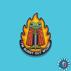 May include: A patch featuring a green frog in a red cape holding a sword, surrounded by flames. The text "I'M BURNT OUT M'LORD" is in a black banner. The patch has a blue background.