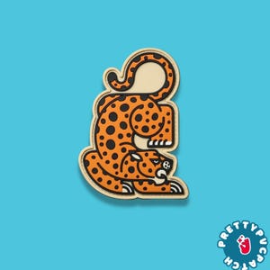 May include: An orange and black leopard patch with a cream-colored border. The leopard is in a crouching position with black spots. The patch has a blue background and a circular logo that says "Pretty Pucatch".