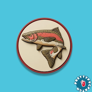 May include: A circular patch featuring a detailed illustration of a rainbow trout. The fish is depicted in shades of brown, red, and beige, set against a cream-colored background with a red border. The patch has the text "PRETTYPUCATCH" in a circle.