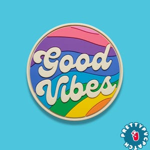 May include: A round patch with the words "Good Vibes" in cream-colored script. The patch features a rainbow design with pink, purple, blue, green, yellow, and orange colors. The patch has a cream-colored border and a blue background.