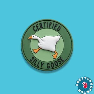May include: A round, green patch with the words "CERTIFIED SILLY GOOSE" encircling a white goose with orange feet and beak. The patch has a 3D effect and is set against a light blue background.