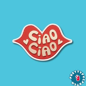 May include: A red lip-shaped patch with a white border featuring the text "CIAO CIAO" in cream-colored, rounded, bold letters. Two small cream-colored hearts are positioned on either side of the text, centered within the red lip shape.