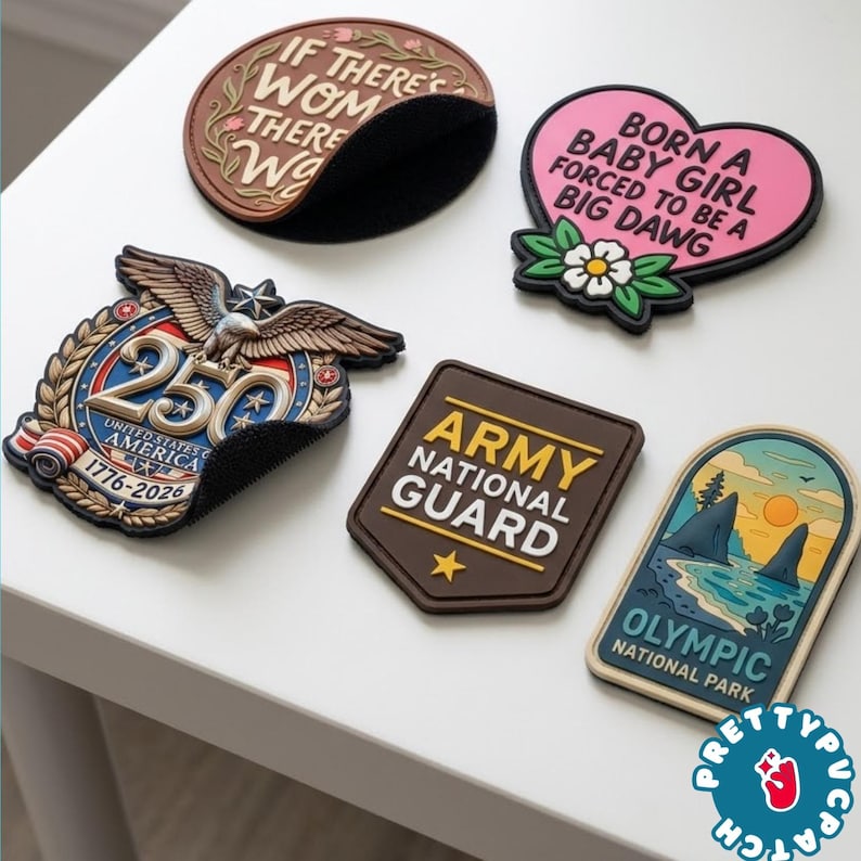 May include: A collection of colorful patches with various designs and text. One patch is a brown oval with the text "IF THERE'S WOM THERE WA". Another is a pink heart with the text "BORN A BABY GIRL FORCED TO BE A BIG DAWG". Other patches include military and patriotic themes.