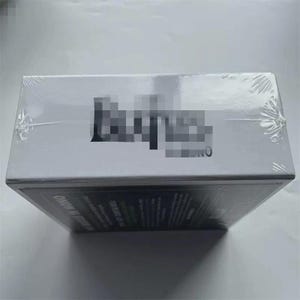 Puede incluir: Una caja blanca, envuelta en plástico transparente, con la palabra borrosa "Beatles" en negro. La palabra "UNO" es visible debajo del texto borroso. La parte inferior de la caja tiene texto en blanco.