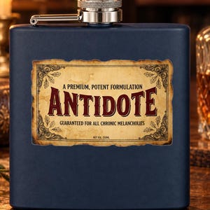 Op de afbeelding: Een matte marineblauwe metalen heupfles met een zilveren schroefdop. De voorzijde heeft een rechthoekig etiket met een perkamentachtige achtergrond, versierde randen en de tekst: A PREMIUM, POTENT FORMULATION ANTIDOTE GUARANTEED FOR ALL CHRONIC MELANCHOLIES NET VOL: 250ML.