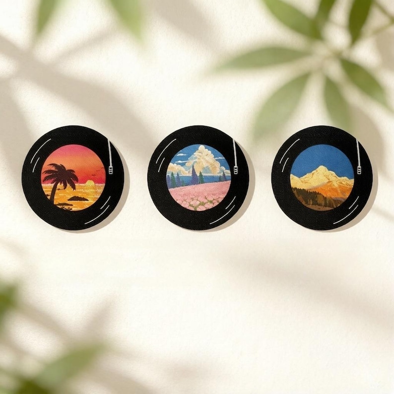 Puede incluir: Tres posavasos circulares dise&ntilde;ados para parecer discos de vinilo negros. Cada posavasos presenta una ilustraci&oacute;n central &uacute;nica: un atardecer tropical con una palmera, un campo de flores rosas bajo un cielo azul y una monta&ntilde;a nevada al atardecer.