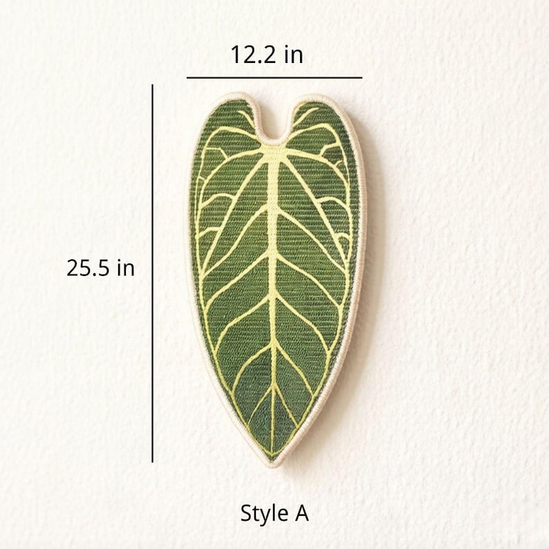 K&ouml;nnte beinhalten: Ein herzf&ouml;rmiger Wandbehang in Blattform mit einer dunkelgr&uuml;nen Oberfl&auml;che und hellgelben Blattadern. Der Artikel ist als Style A gekennzeichnet und zeigt Ma&szlig;e von 31 cm Breite und 64,8 cm H&ouml;he, die die physische Gr&ouml;&szlig;e des Objekts angeben.