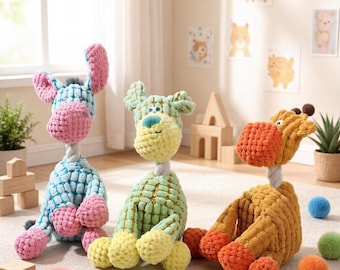 May include: Three plush animal toys with a textured, grid-like fabric surface. The left toy is light blue and pink, the centre toy is light green, and the right toy is golden yellow and orange. Each features a rope neck and rounded limbs.