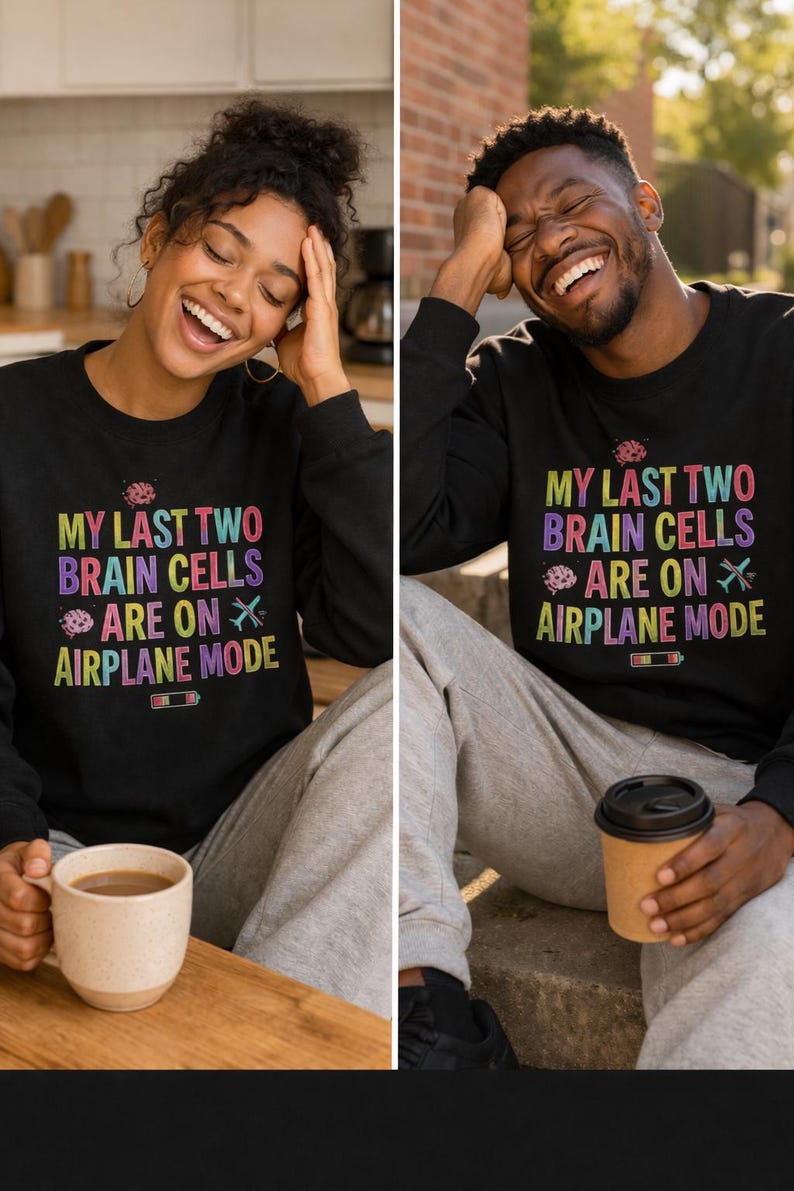 May include: Black long-sleeve shirt with the text "MY LAST TWO BRAIN CELLS ARE ON AIRPLANE MODE" in colorful letters. The shirt is worn by a person. A coffee mug is in the person's hand.