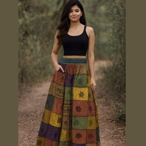 May include: A black tank top paired with a long patchwork skirt. The skirt features a variety of colors including brown, purple, green, and yellow, with floral and geometric patterns. The skirt has a high waist and a flowing silhouette.