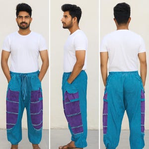 May include: Teal and purple patchwork pants with a drawstring waist. The pants have large purple pockets on the sides and are made of a soft, lightweight fabric. The model is wearing a white t-shirt.