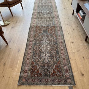 May include: A long, rectangular rug with an intricate, traditional design. The rug features a central medallion and border in shades of red, blue, and beige. The rug is placed on a hardwood floor.