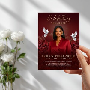 May include: A funeral program card featuring a deep red background with dark roses, two white doves, and a portrait of a person in a red top. The text reads Celebrating the life of Emily Sophia Carter, April 10, 1984 &ndash; January 6, 2026.