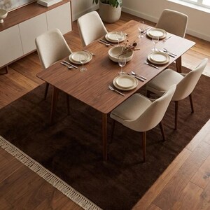 Premium chocolate brown hand-knotted rug made of 100% New Zealand wool, featuring a solid contemporary design with contrasting fringed edges, styled under a mid-century coffee table in a modern minimalist living room.