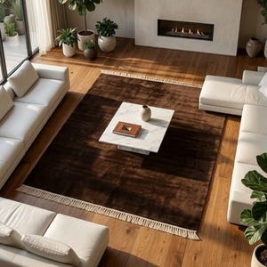 Premium chocolate brown hand-knotted rug made of 100% New Zealand wool, featuring a solid contemporary design with contrasting fringed edges, styled under a mid-century coffee table in a modern minimalist living room.