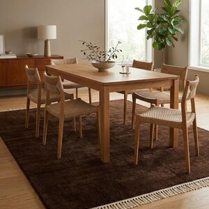 Premium chocolate brown hand-knotted rug made of 100% New Zealand wool, featuring a solid contemporary design with contrasting fringed edges, styled under a mid-century coffee table in a modern minimalist living room.