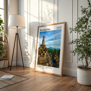 May include: A framed vertical wall art print featuring a photograph of the Borobudur temple in Central Java, Indonesia. The print includes the text Borobudur, INDO, and the geographic coordinates 7.6079 S, 110.2037 E printed in black ink.