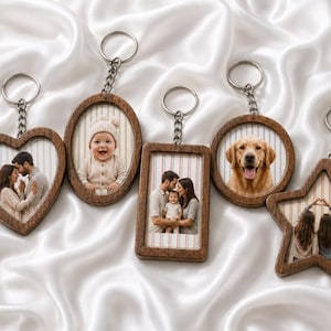 May include: A collection of five wooden keychains in heart, oval, rectangular, circular, and star shapes. Each keychain features a metal ring and chain, holding a photograph of people or a dog against a vertical striped background.