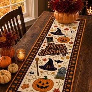 May include: A quilted table runner featuring a cream background with the text Happy Halloween in black script. The design includes orange jack-o'-lanterns, purple witch hats, a skull, a broom, a tombstone with RIP, a ghost, and autumn leaves.