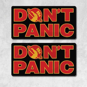 Puede incluir: Dos pegatinas rectangulares negras con las palabras "DON'T PANIC" en rojo, delineadas en negro. La palabra "DON'T" tiene un gráfico amarillo de una mano y un planeta. Las pegatinas son resistentes al agua, al combustible, al aceite, a los productos químicos y a los arañazos, con protección UV.