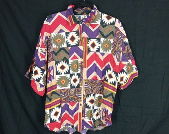 May include: A short-sleeved button-down shirt with a colorful geometric pattern. The pattern features a mix of red, purple, green, yellow, and white.