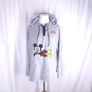 May include: A gray fleece hoodie with a half-zip closure. The hoodie features a Mickey Mouse graphic with the word "Mickey" embroidered in red on the front.