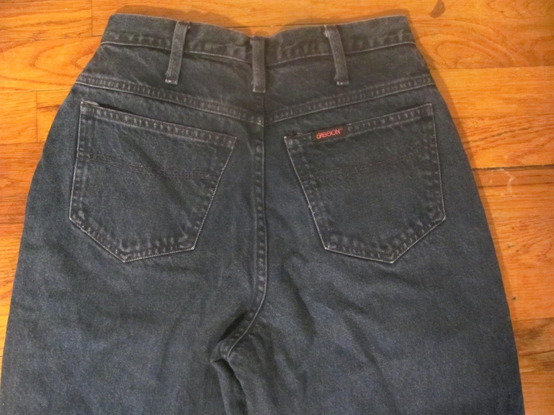 May include: A pair of dark blue denim jeans with a back pocket that has the word "GRACIOUS" stitched on it.