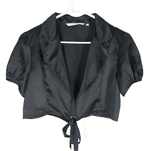 May include: A black satin cropped jacket with a tie front and short sleeves. The jacket has a collar and is made of a soft, silky fabric.