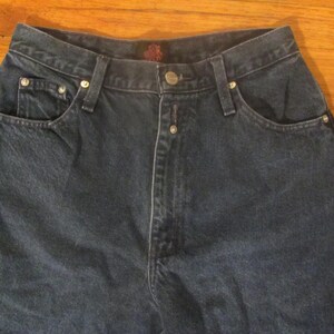 May include: A pair of dark blue denim jeans with a button fly and five pockets.