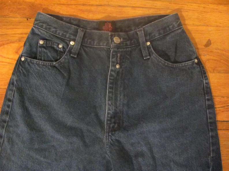 May include: A pair of dark blue denim jeans with a button fly and five pockets.