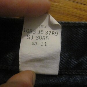 May include: A white tag with black text that reads "Style 1083 J5 3789 SJ 3085 Size 11" attached to a dark blue denim fabric.