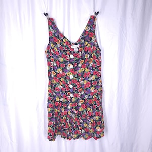 May include: A black sleeveless dress with a floral print in shades of red, yellow, and purple. The dress has a button-up front and a ruffled hem.