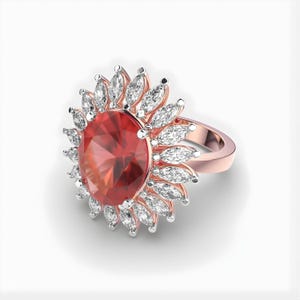 Puede incluir: Anillo de oro rosa con una gran gema roja de corte ovalado rodeada de gemas blancas más pequeñas con forma de marquesa. El diseño del anillo es floral, con las gemas dispuestas en halo. Joya.