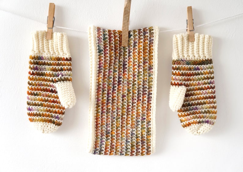 May include: A set of crocheted fingerless gloves and a matching scarf in a multi-colored yarn with shades of brown, orange, and purple. The yarn has a speckled effect.