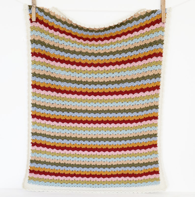 May include: A multi-colored striped crochet baby blanket with a white crocheted border. The blanket features stripes of red, pink, blue, green, yellow, and brown.