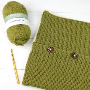 May include: A green crocheted cushion with two wooden buttons. The cushion has a white border. A ball of green yarn and a crochet hook are also in the image. The yarn label reads "Essential DK"