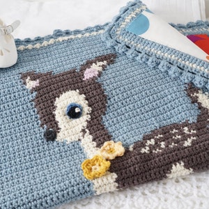 May include: A blue crocheted baby blanket with a brown and white deer design and yellow flower accents.