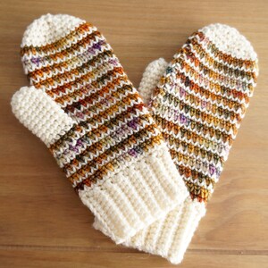 May include: A pair of crocheted mittens with a striped pattern in shades of brown, orange, and white.