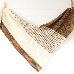 May include: A triangular shawl with a white centre and a brown, multi-coloured border. The shawl is crocheted and has a fringed edge.