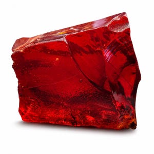 Peut inclure: Un gros morceau irrégulier de verre rouge translucide avec une surface lisse et polie. Le matériau présente des teintes cramoisies profondes et une réfraction interne de la lumière, avec des bords tranchants et une texture brillante.
