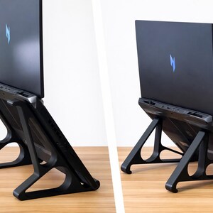 May include: Black laptop computer on a black laptop stand. The laptop has a blue logo on the back. The stand is made of black plastic and has a unique, open design. The laptop is angled upwards.