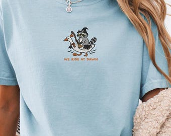 Funny Raccoon Shirt, Embroidered Raccoon Goose Shirt, Cute Animal Gift, We Ride at Dawn, Ren Faire Clothing, Witchy Silly Goose Lover Tee