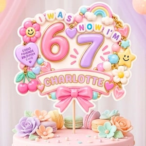 Pode incluir: Um topo de bolo com o texto I WAS NOW I'M 6 7 e CHARLOTTE, decorado com um número 6 rosa, um número 7 roxo, um arco-íris, uma flor sorridente, uma estrela amarela, cerejas, corações e um laço rosa num palito de madeira.